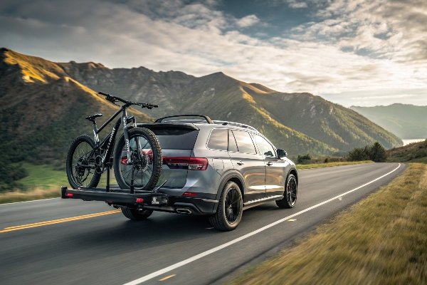 A bicycle on a hitch rack with a durable, snug-fitting transport cover, driving down a highway