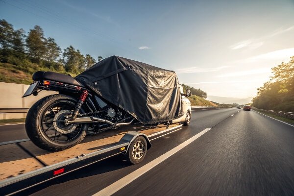 Secure motorcycle cover for trailering at high speeds A motorcycle on a trailer with a very snug-fitting cover secured with multiple straps